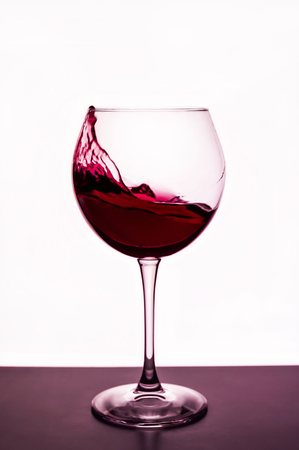 splashes of red wine in a wineglassの写真素材