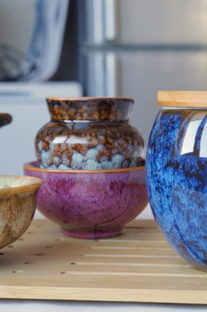 Handcrafted ceramic tea bowls are arranged in a softly lit home interior. The image represents