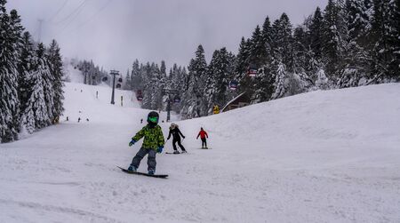 Cute, young boy snowboarding, in the chairlift on the way to the mountain peak, looking trough the icy window.の写真素材