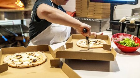Young woman slicing up pizza.の写真素材