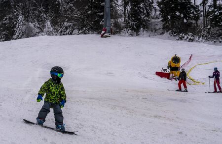 Cute, young boy snowboarding, in the chairlift on the way to the mountain peak, looking trough the icy window.の写真素材