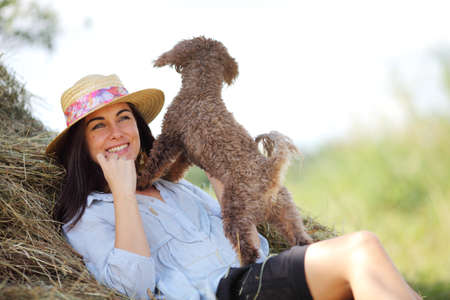 girl next to a stack of hay with dogの写真素材