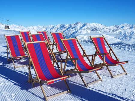 Empty deckchairs in front of ski slopes in alps mountainsの写真素材