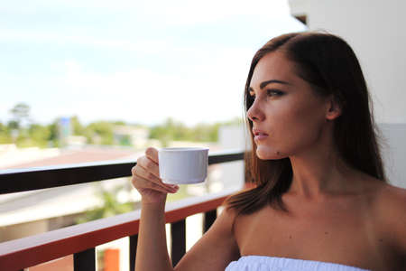 Beautyful woman drinks a coffee on a balconyの写真素材