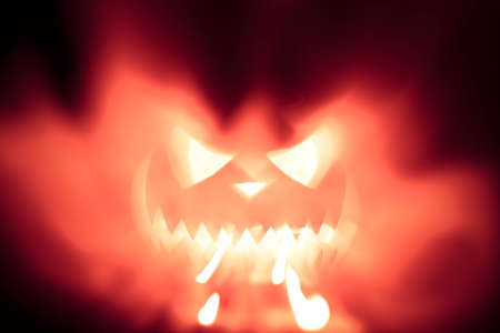 Spooky halloween pumpkin shiny inside on black backgroundの写真素材