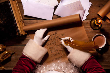 Santa Claus sitting at his room and writing Christmas letter or wish listの写真素材