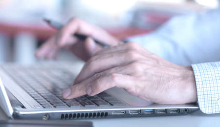 Closeup of a male hands busy typing on a laptopの写真素材