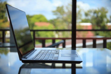Conceptual green workspace, Laptop on table and green garden background, business technology conceptの写真素材