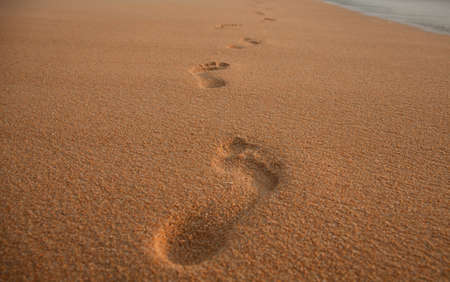 Mans footspeps in the sand at sunsetの写真素材