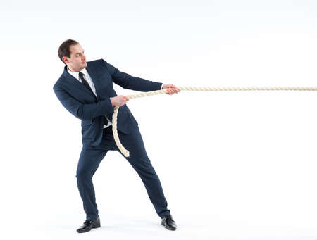 Strong and confident business leader. Side view of businessman in suit pulling a rope while standing...