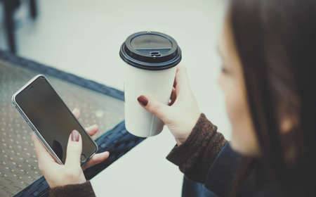 Woman with smartphone drinking coffee.の写真素材