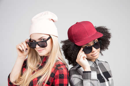 Studio lifestyle portrait of two best friends hipster girls going crazy and having great time together. Isolated on white background.の写真素材