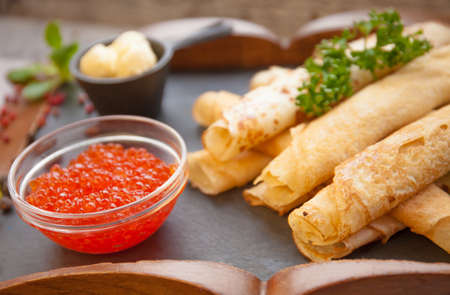 Pancakes with red caviar and cream.