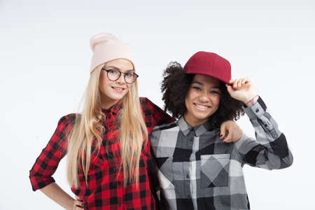 Studio lifestyle portrait of two best friends hipster girls going crazy and having great time together. Isolated on white background.の写真素材