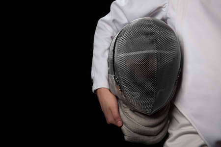 Fencer woman hold her helmet in hand wearing white fencing costume. Isolated on black background.の写真素材