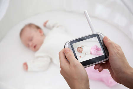 Hand holding video baby monitor for security of the babyの写真素材