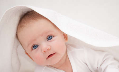 little baby under a white towel looking at the camera