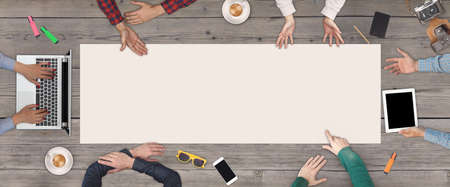Business Teamwork concept - top view of six business people. White blank sheet of paper in the middle of the wooden table.の写真素材
