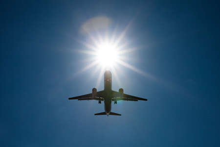 Silhouette passenger airplane against bright sun