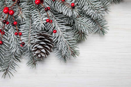 Christmas card. White wooden background with snow fir tree and decoration. Top view with copy space...