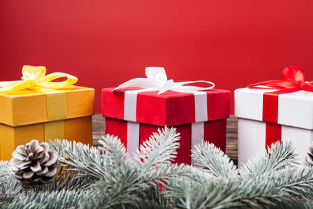 Christmas gifts presents on red background. Snow fir tree white and golden and red gift boxes with...