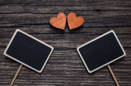 Valentines day concept. Two red hearts and two black plank for text on old wooden background.