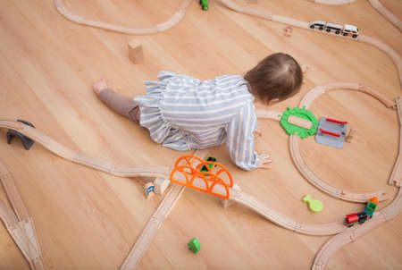 Cute kid playing with toy railway road at homeの写真素材