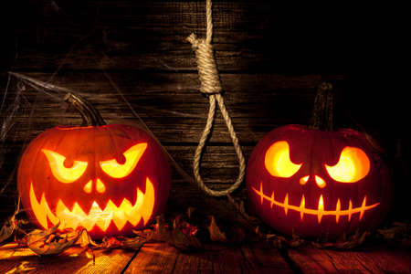 Two Halloween pumpkin head jack on dark wooden backgroundの写真素材