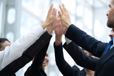 Happy successful multiracial business team giving a high fives gesture as they laugh and cheer their...