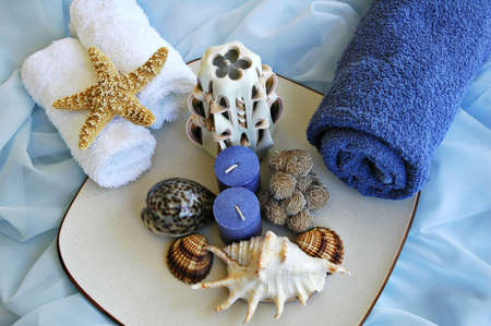 Seashells, towels and candles on blue silk clothの写真素材