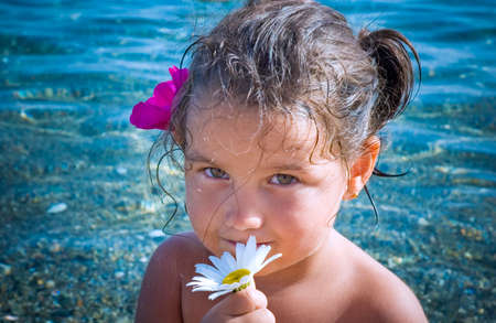A beautiful 4 year old playing with flowers at the beachの写真素材