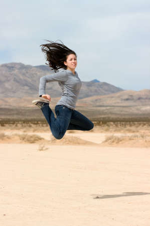 A young happy girl jumping in the Nevada desert ( dry lake bed)の写真素材