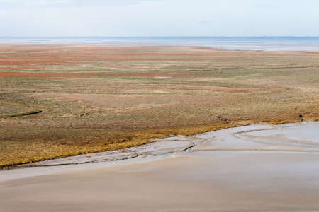 Sea coast at low tide. The tides can vary greatly, at roughly 14m between high and low water marks. One of France's most recognizable landmarks. View from the top of the mount Saint Michael's, Franceの写真素材