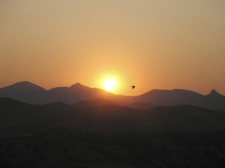 Sunset on a background of mountains and flying birds.の写真素材