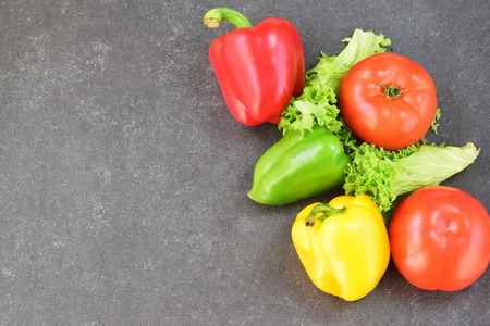 Fresh vegatables: paprika, tomato, onion,onion, carrot on a rustic textile cloth on a grey wooden background. Healthy eating concept. Place for text.の写真素材