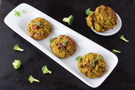 Broccoli balls deep fried on a white plate with tomato sauce with fresh broccoli on a black abstract background. Healthy eating concept. Dietingの写真素材