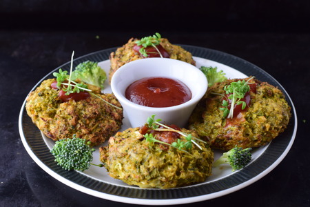Broccoli balls deep fried on a white plate with tomato sauce with fresh broccoli on a black abstract background. Healthy eating concept. Dietingの写真素材