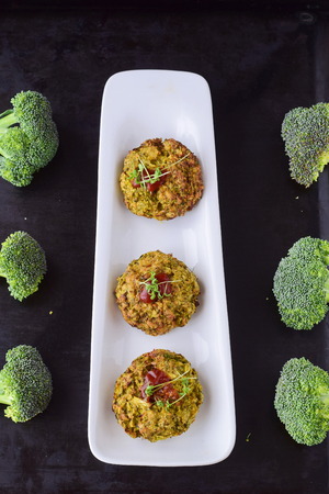Broccoli balls deep fried on a white plate with tomato sauce with fresh broccoli on a black abstract background. Healthy eating concept. Dietingの写真素材
