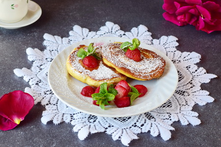Pancakes with strawberry inside in a white plate on a white lace textile. Healthy breakfast. Healthy...