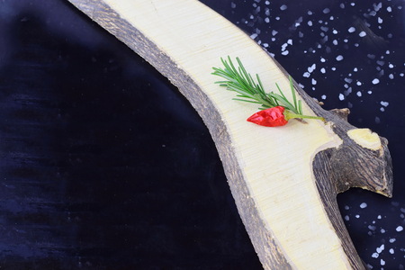 Spices and herbs on a black background with wooden element asideの写真素材