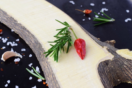 Spices and herbs on a black background with wooden element asideの写真素材
