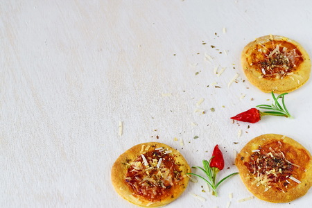 Homemade biscuits in a form of pizza on a white abstract background with chili peppers and rosemary. Space for textの写真素材