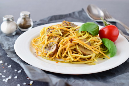 Pasta with mushrooms and pesto sauce in a white plate on abstract bckground. Italian lifestyle. Healthy eating conceptの写真素材