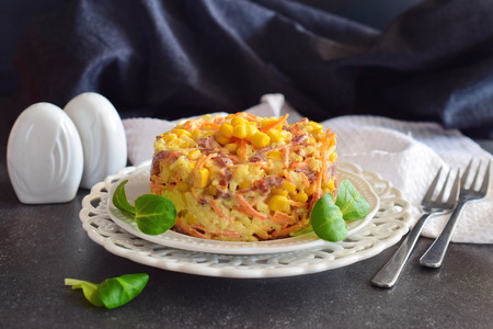 Salad with smoked sausage, corn, cheese, fresh carrot, egg, garlic and yogurt on a white plate on a abstract backgroundの写真素材