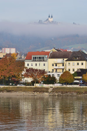 Autumn day in Linz, Austria with beautiful reflection and Postlingberg in the fog, vertical.の写真素材