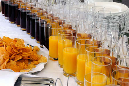 Rows of glasses of juice and a pile of chipsの写真素材