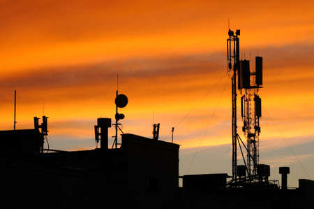 Silhouette of mobile communication antennas in an orange sunsetの写真素材