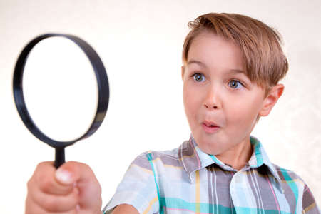 Boy looking through a magnifying glassの写真素材