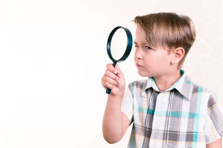 Boy looking through a magnifying glassの写真素材