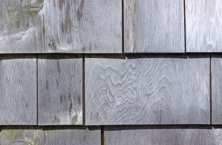A few cedar shingles on an exterior wall weathered from the elements.